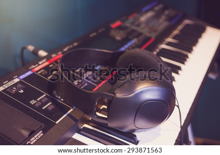 Close up of headphone on keyboard in music studio room, music instrument concept, vintage pastel tone