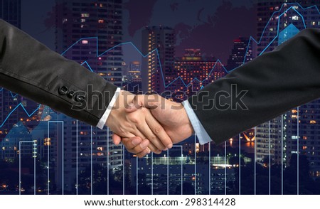 Hand shake between businessman on Trading graph on the cityscape at night and world map background,Business financial concept