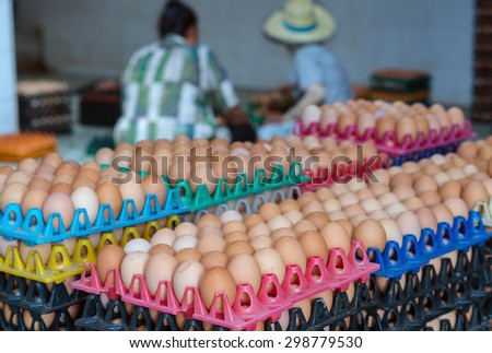 Stack of eggs in chicken farm with worker blurred background