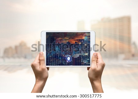 female hands holding a tablet that show business trading graph on cityscape blurred background,business investment concept