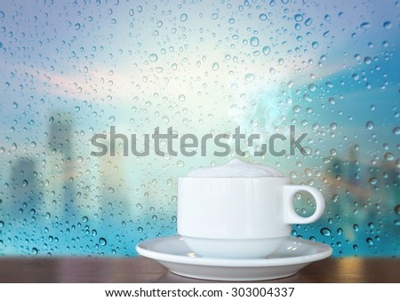 White coffee cup with smoke on a glass surface windows with cityscape background
