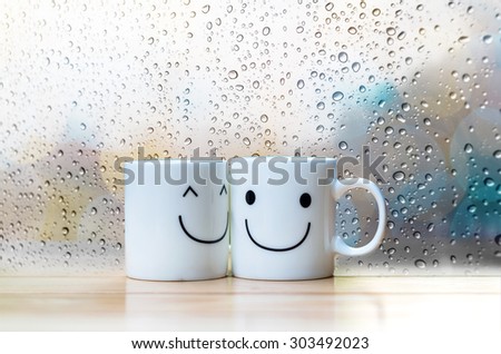 Two happy cups on the wood table with glass surface windows, about love concept