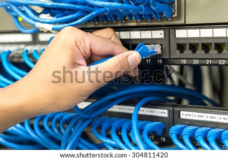 hand holding and pluging network cable connect to router and switch hub in server room