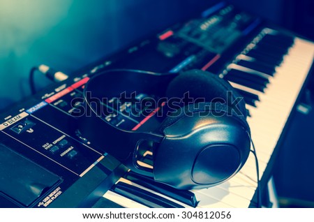 Close up of headphone on keyboard in music studio room, music instrument concept, blue color tone