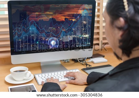 Rear view of a businessman working with a computer and tablet of business trading graph at screen on the office desk