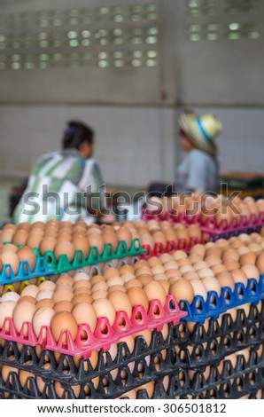Stack of eggs in chicken farm with worker blurred background