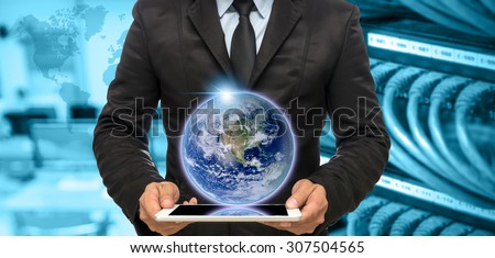 Businessman holding the tablet on Abstract blurred photo of empty computer room with earth and world map,Elements of this image furnished by NASA