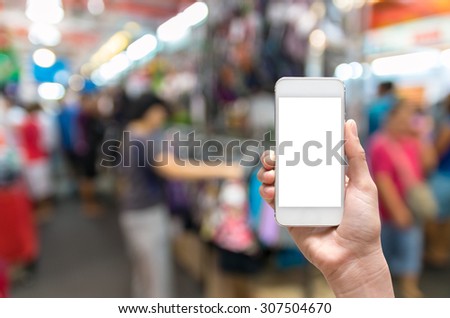 Female hand holding mobile smart phone touch screen on Abstract blurred photo of store blur with customer choose product bokeh background