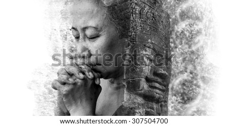 Double exposure and Disintegration of old woman praying with face of Bayon Temple at Angkor Thom
