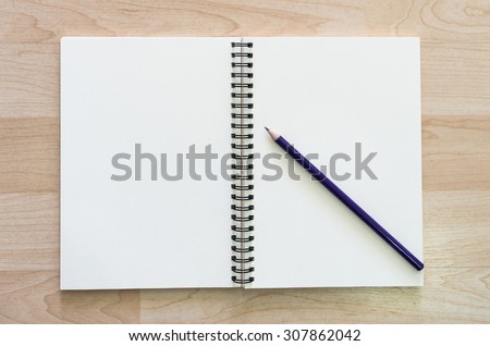 Pencil on the open leather book with wooden background