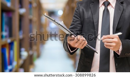 Businessman writing the file pad on the Abstract blurred photo of library background