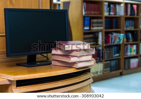 old book on the desk with computer monitor in library