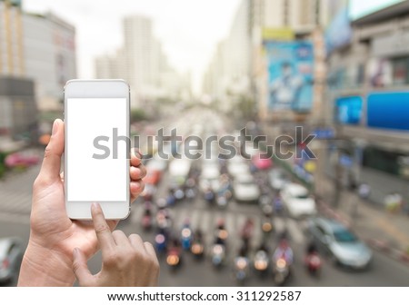 Female hand holding mobile smart phone on abstract Blurred photo of traffic jam with rush hour