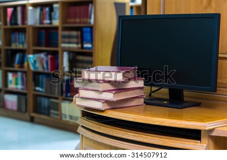 old book on the desk with computer monitor in library