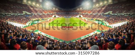 Abstract blurred photo crowd of spectators on a stadium with a football match, sport background concept