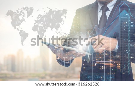 Double exposure of businessman using the tablet with cityscape and financial graph on blurred building with world map and people logo background, Elements of this image furnished by NASA