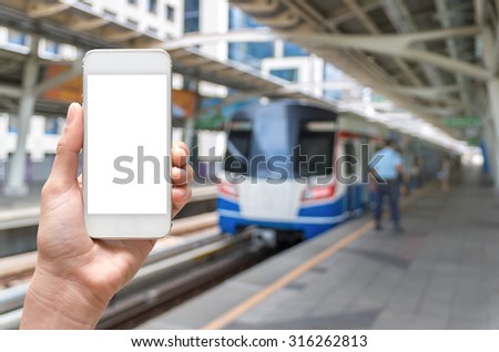 Hand holding tablet taking photo on abstract Blurred photo of sky train at station with security guard