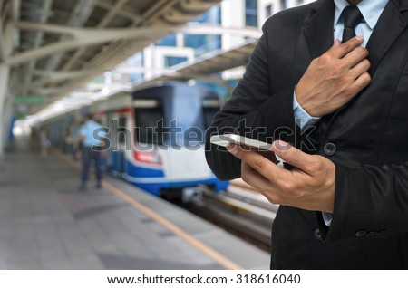 Businessman using the smart phone on abstract Blurred photo of sky train at station with security guard
