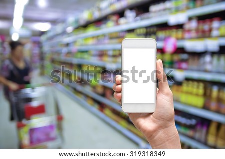 Female hand holding mobile smart phone touch screen on Abstract blurred photo of store with trolley in department store bokeh background