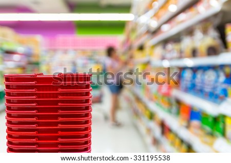 Abstract blurred photo of store with trolley and red color basket in department store bokeh background, business concept