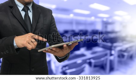 Businessman using the tablet on Abstract blurred photo of empty computer room, education and business concept