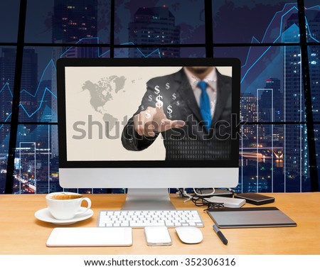 Workspace with computer desktop with Businessman point sign of money at the screen on the trading graph over the blurred photo of cityscape background,Elements of this image furnished by NASA