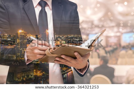 Double exposure of Businessman writing the note book on the Abstract blurred photo of conference hall or seminar room with attendee background