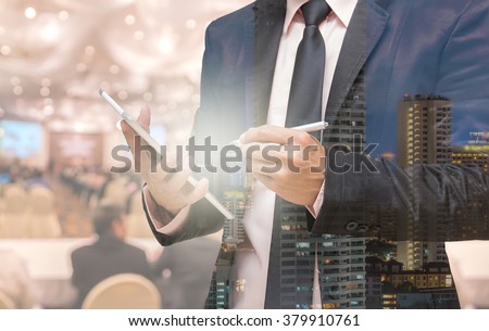 Double exposure of Businessman using the tablet on the Abstract blurred photo of conference hall or seminar room with attendee background