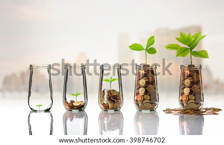 Gold coins and seed in clear bottle on cityscape photo blurred cityscape background,Business investment growth concept