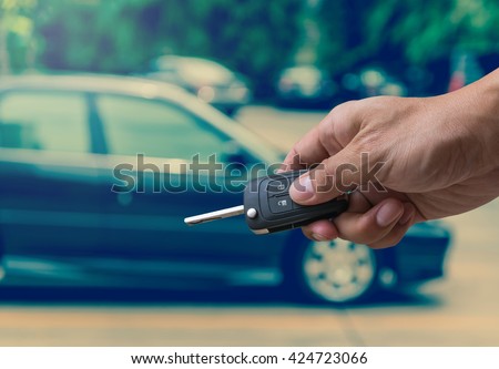 Hand holding and touching the keys over photo blurred of used car for open the door car, transportation and ownership concept, car key concept