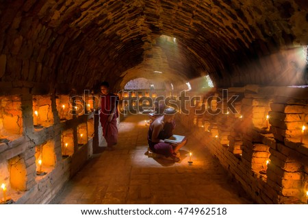 Three Young Buddhist Monk are reading with sun light from outside to inside pagoda of old bagan, mandalay, myanmar