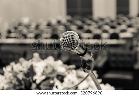 Microphone over the Abstract blurred photo of conference hall or seminar room background, vintage color tone