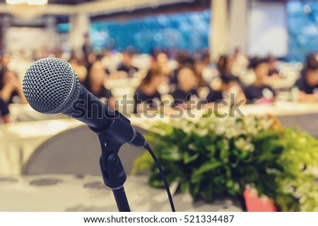 Microphone over the Abstract blurred photo of conference hall or seminar room with attendee background, business seminar concept