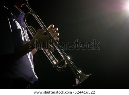 Young student Musician playing the Trumpet with spot light and len flare over dark background on the stage, Musical concept