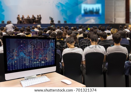 Computer set showing the Trading graph on the cityscape at night over the Abstract blurred photo of seminar room with attendee background,business and education concept