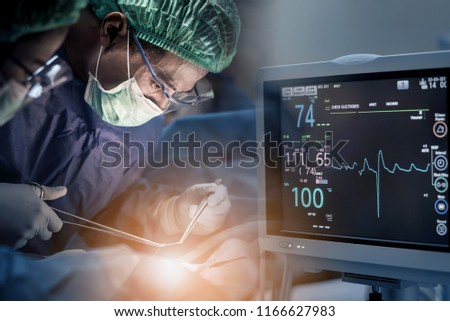 Team of doctors or surgeons with electrocardiogram monitor in hospital surgery operating emergency room showing patient heart rate, medical rescue concept.