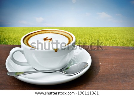 Cappuccino coffee with paddy rice field at sunrise background