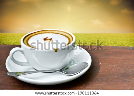 Cappuccino coffee with paddy rice field at sunrise background