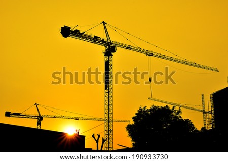 Hoisting crane silhouettes at sunset