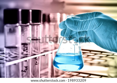 Flask in scientist hand with test tubes in rack