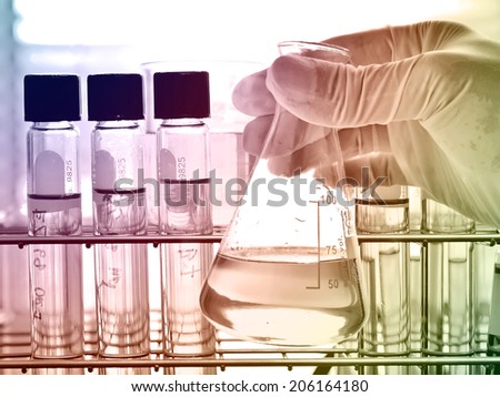 Flask in scientist hand with test tubes in rack