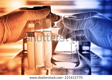 Laboratory research, flask in scientist hand with laboratory glassware
