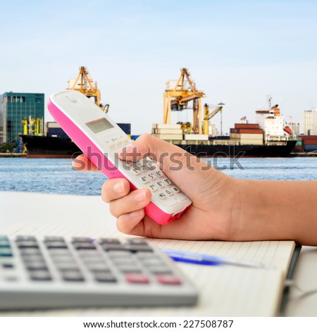 Telephone in woman hand with cargo crane at sea port background