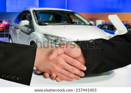 Business handshake closing a deal with car exhibition background