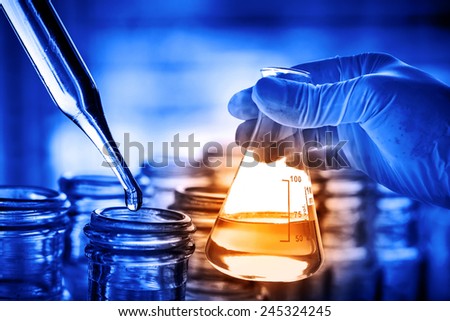 Flask in scientist hand with dropping chemical liquid to test tube
