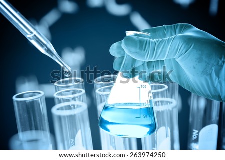 Flask in scientist hand with dropping chemical liquid to test tubes