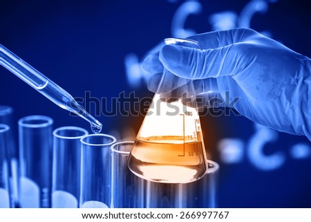 Conical flask in scientist hand with dropping chemical liquid to test tube