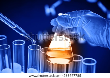 Conical flask in scientist hand with dropping chemical liquid to test tube