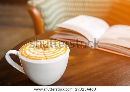 cappuccino coffee with blur book background, warm light tone