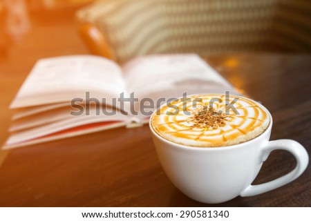 Cup of cappuccino coffee with blur book background, warm light tone